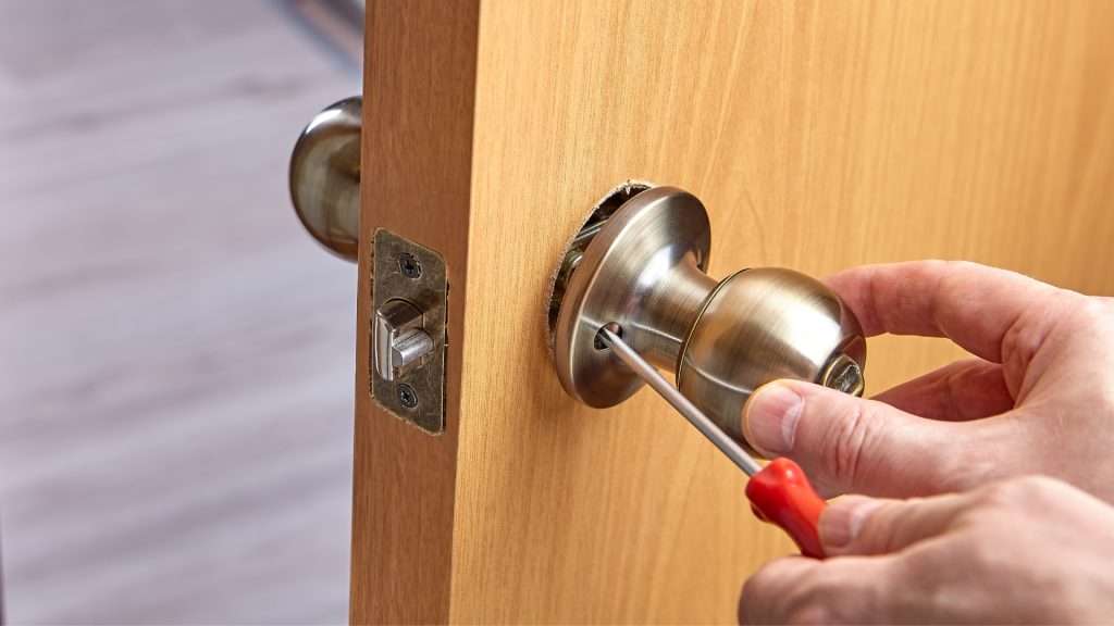 A locksmith performing door lock replacement