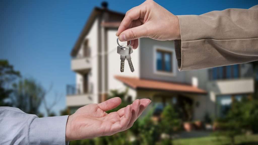 A person handing over spare keys to another person