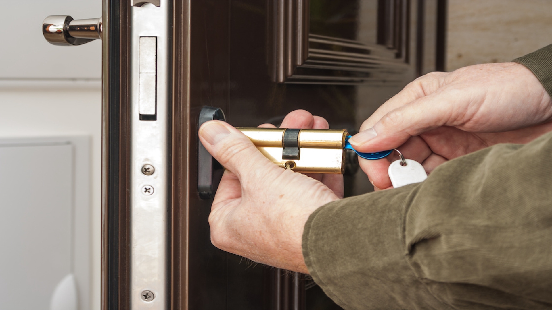 A locksmith is working on rekeying a lock on a door to save cost.