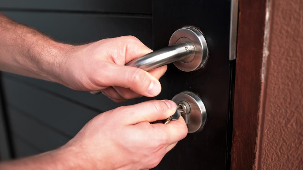 Close-up of a person unlocking a front door, representing the decision to rekey or replace locks for better home security after moving