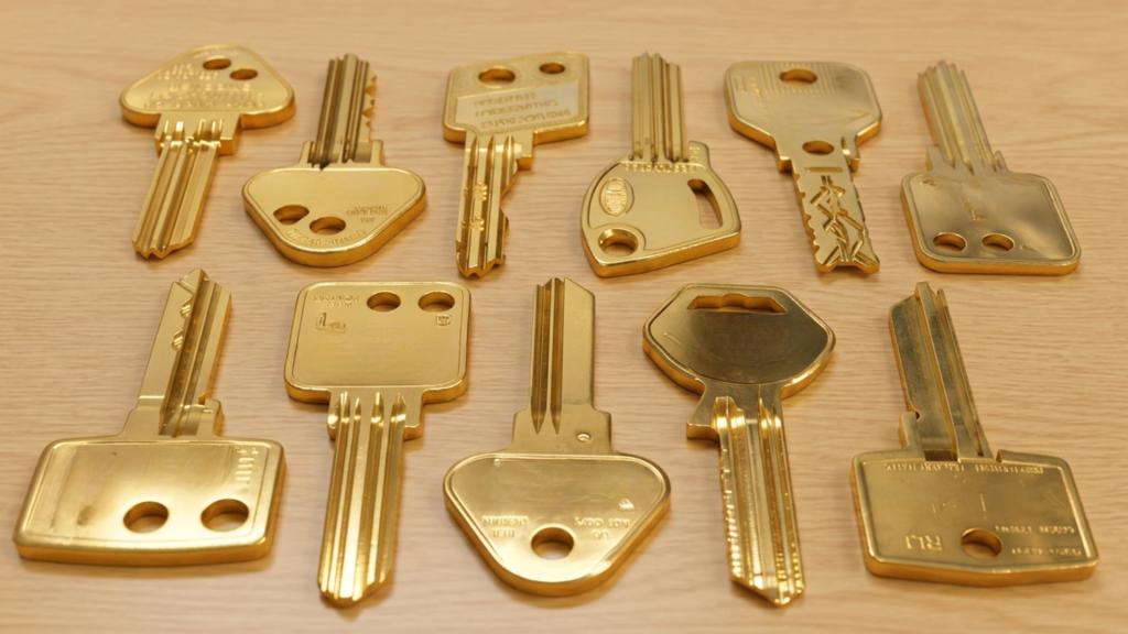 Collection of restricted keyway keys displayed on a wooden surface showing specialty keys used for key control and improved security